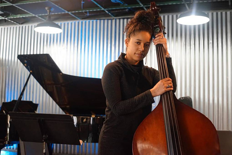 Aneesa Strings with her bass during a workshop, piano in the background.